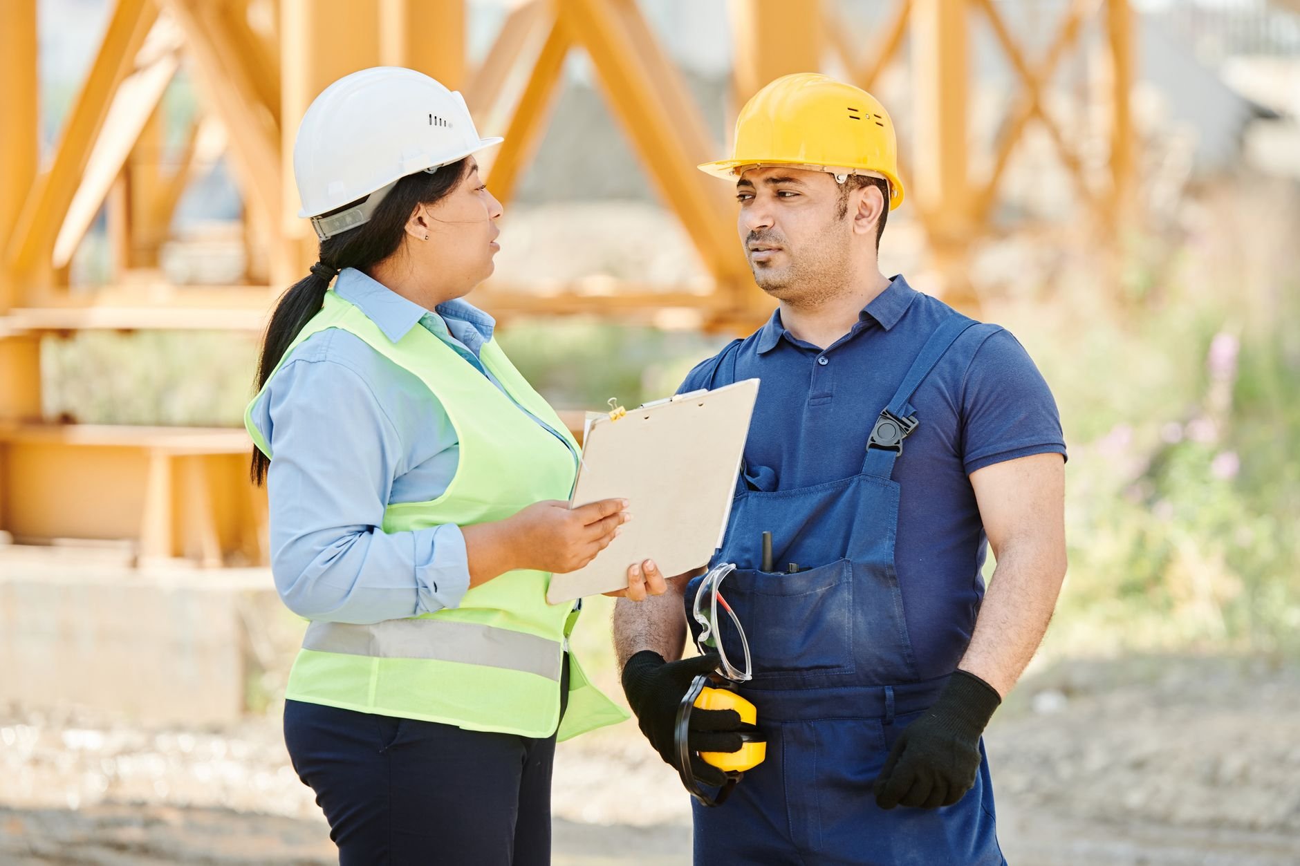 Male and female construction workers talking with safety gear at an outdoor site